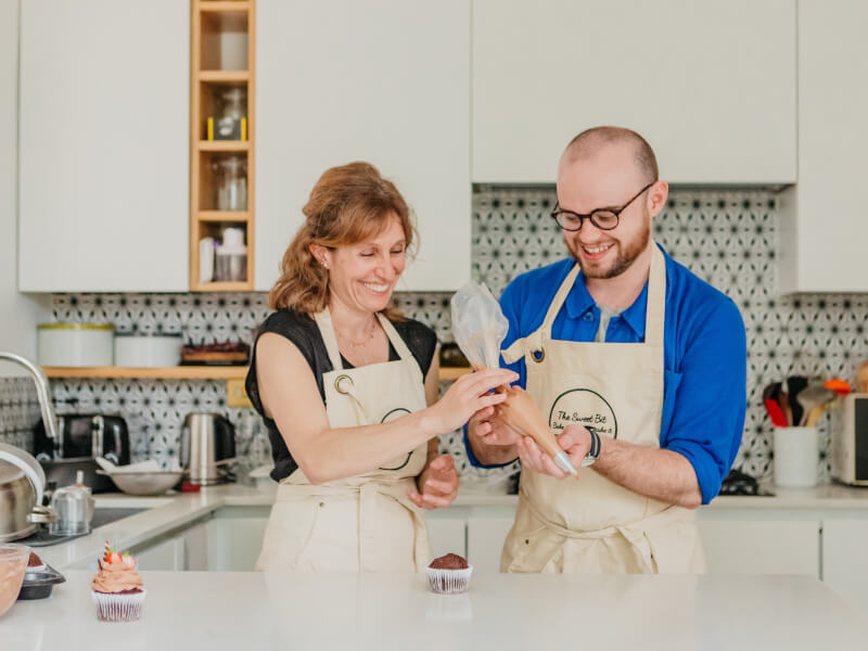 A mother and son enjoy a cupcake making class together